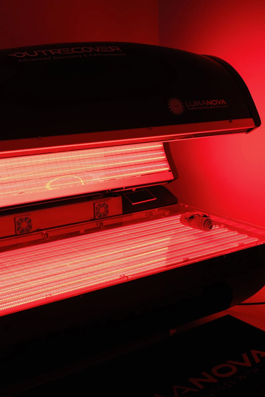 The red light therapy bed open and lit at OutRecover in Naples, FL